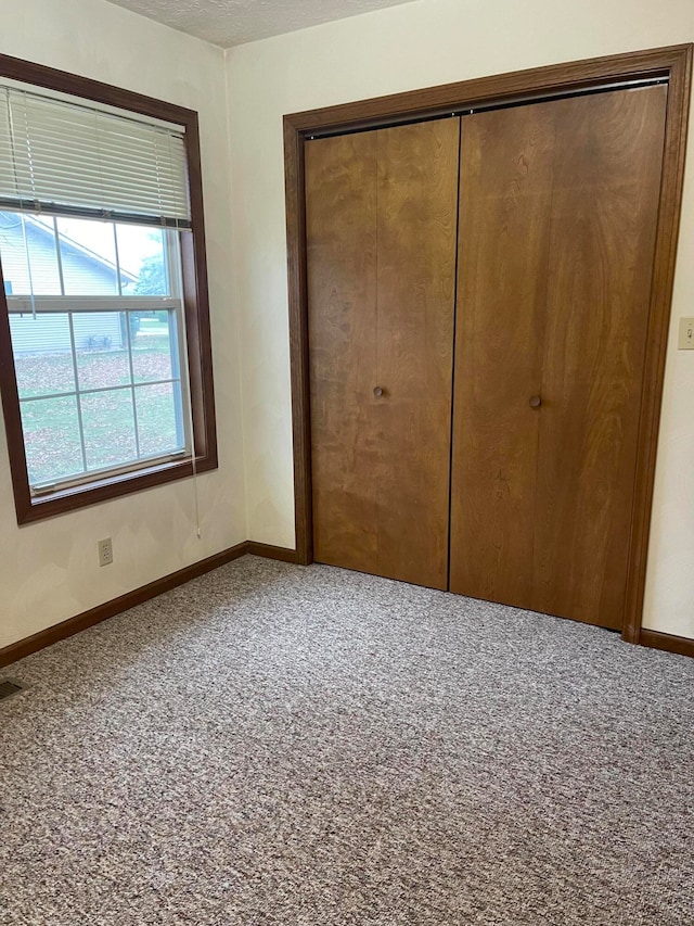 unfurnished bedroom featuring a closet, carpet floors, and a textured ceiling