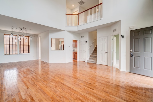 unfurnished living room with a high ceiling and light hardwood / wood-style flooring