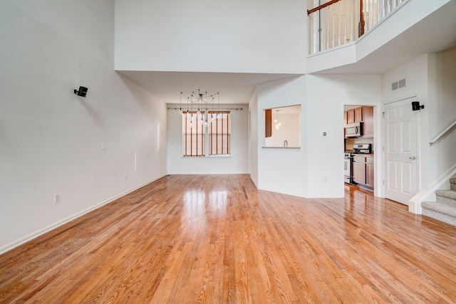 unfurnished living room with light hardwood / wood-style flooring and a towering ceiling