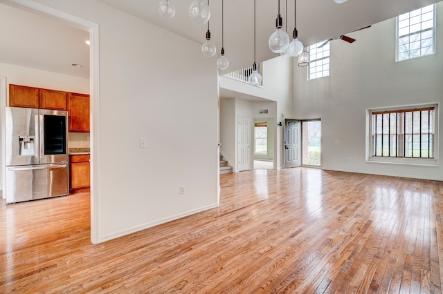 unfurnished living room with light hardwood / wood-style flooring and a high ceiling