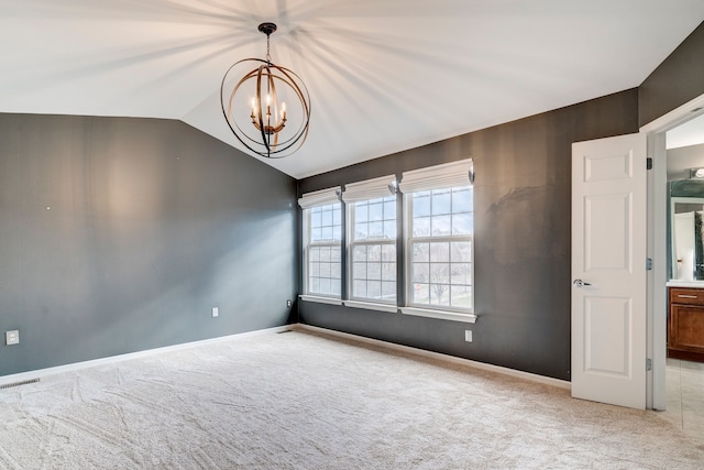 spare room with light carpet, lofted ceiling, and a notable chandelier