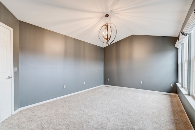 spare room with carpet floors, vaulted ceiling, and an inviting chandelier