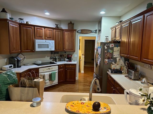 kitchen featuring hardwood / wood-style floors, white appliances, and sink