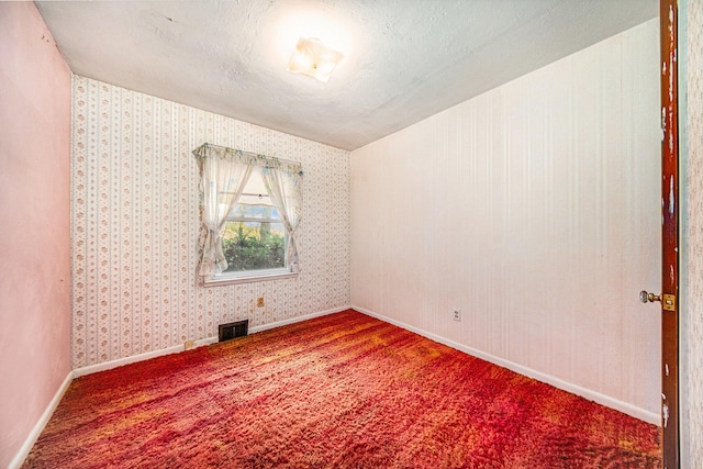 empty room with carpet floors and a textured ceiling