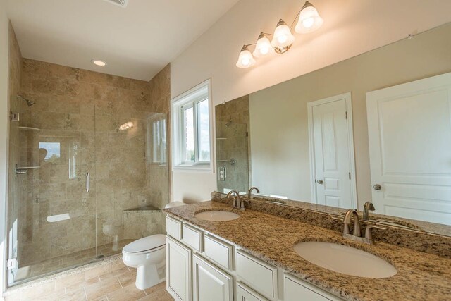 bathroom with vanity, toilet, and a shower with door