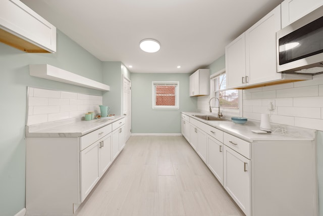 kitchen with tasteful backsplash, white cabinetry, and sink