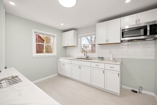 kitchen featuring backsplash, white cabinetry, and sink