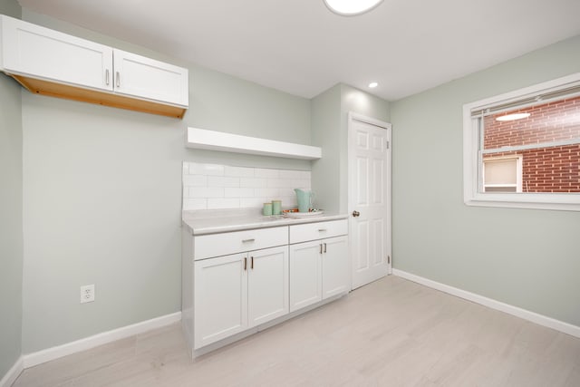 kitchen with decorative backsplash, light hardwood / wood-style floors, and white cabinetry