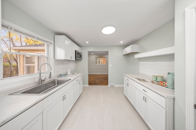 kitchen featuring white cabinets, tasteful backsplash, light hardwood / wood-style flooring, and sink