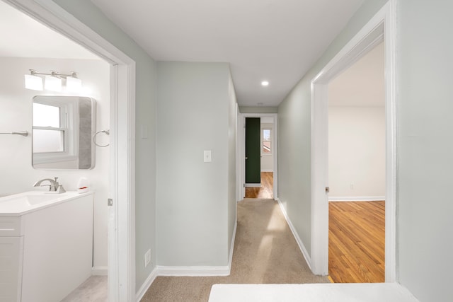 hallway with light hardwood / wood-style flooring, a wealth of natural light, and sink