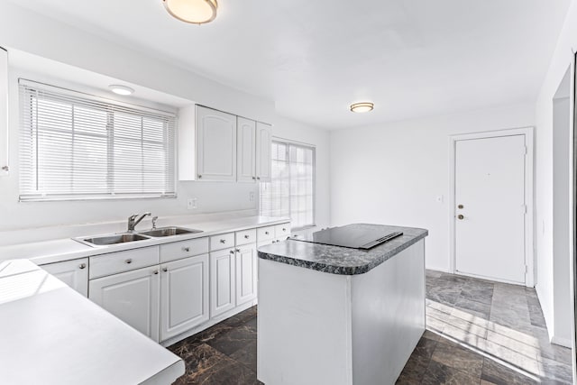 kitchen with white cabinets, black electric cooktop, a kitchen island, and sink