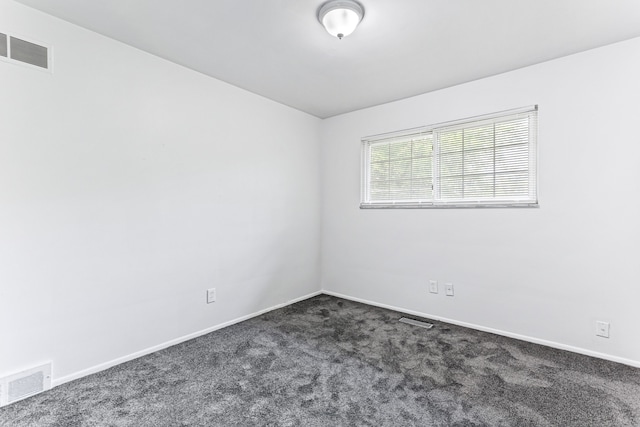 spare room with dark carpet