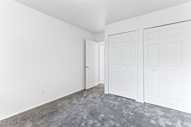 unfurnished bedroom featuring dark colored carpet and multiple closets