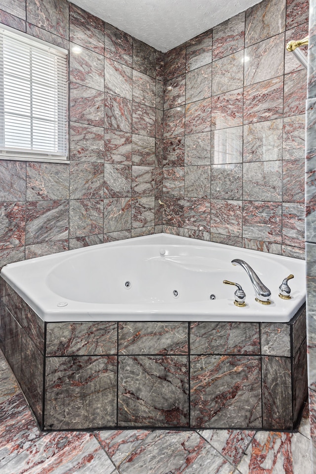 bathroom with a textured ceiling, tiled tub, and tile walls