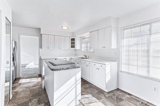 kitchen with a center island, white cabinets, stainless steel refrigerator with ice dispenser, and sink