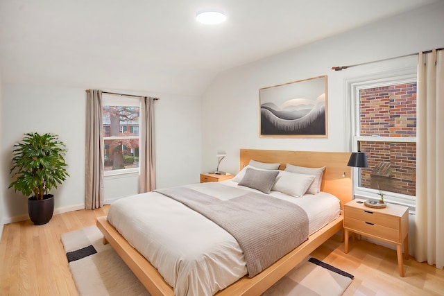 bedroom with lofted ceiling and light wood-type flooring