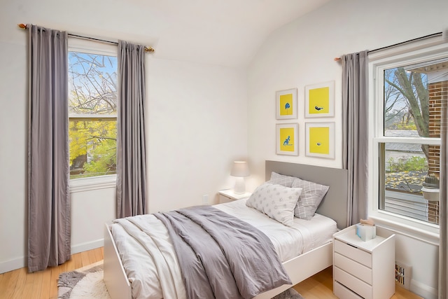 bedroom with light hardwood / wood-style flooring, multiple windows, and lofted ceiling