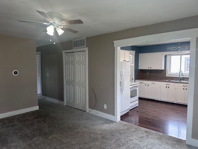 kitchen with white appliances, white cabinets, sink, tasteful backsplash, and dark hardwood / wood-style flooring