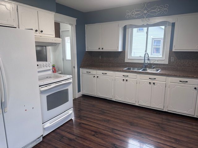 kitchen with white appliances, backsplash, sink, dark hardwood / wood-style floors, and white cabinetry