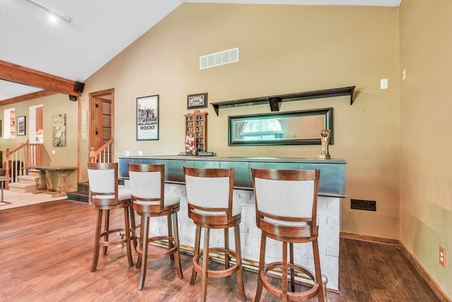 bar with wood-type flooring, rail lighting, and high vaulted ceiling