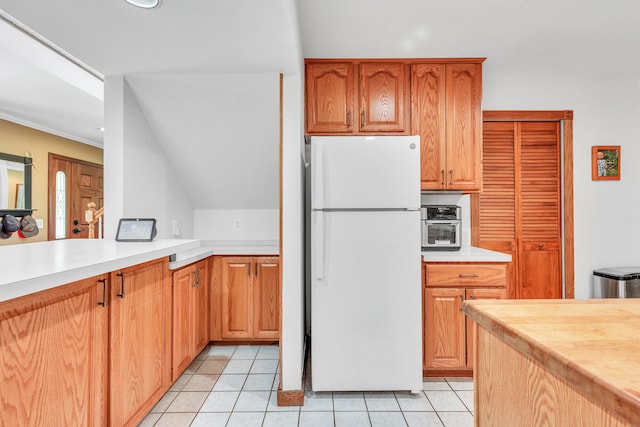 kitchen with crown molding, light tile patterned floors, and white refrigerator