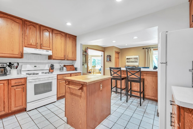 kitchen featuring decorative backsplash, plenty of natural light, a kitchen island, and white appliances