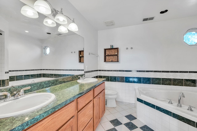 bathroom featuring vanity, tile patterned flooring, toilet, tile walls, and tiled bath