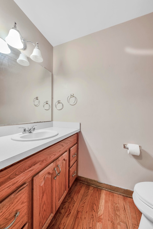 bathroom with hardwood / wood-style floors, vanity, and toilet