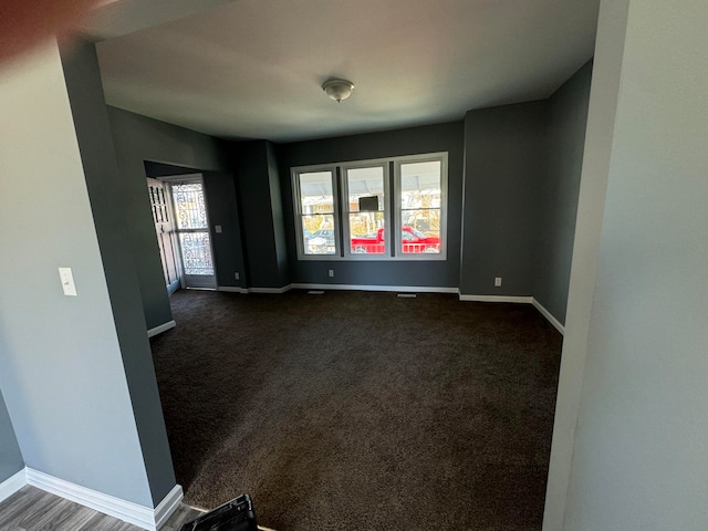 unfurnished room featuring dark carpet