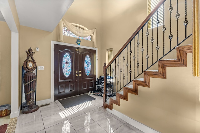 foyer featuring light tile patterned flooring and a towering ceiling