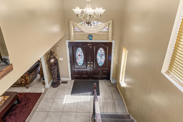 tiled entrance foyer with a high ceiling and a notable chandelier