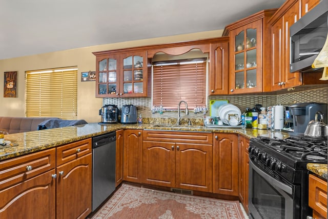 kitchen featuring decorative backsplash, stone counters, sink, and appliances with stainless steel finishes