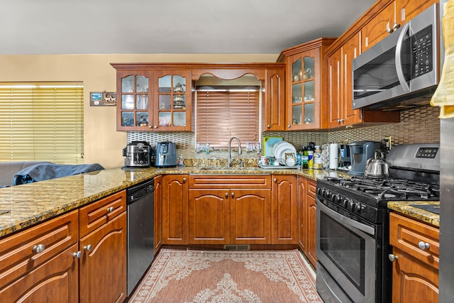 kitchen featuring backsplash, light stone counters, sink, and stainless steel appliances