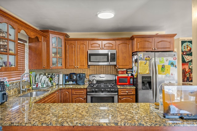 kitchen featuring tasteful backsplash, light stone counters, sink, and appliances with stainless steel finishes