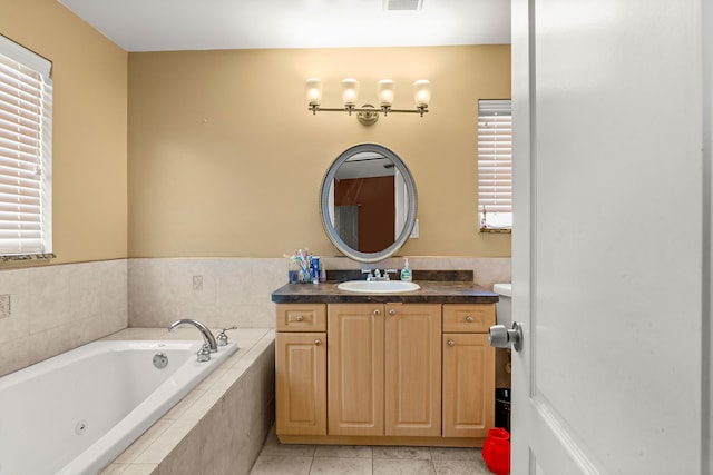 bathroom with tile patterned floors, vanity, and a relaxing tiled tub