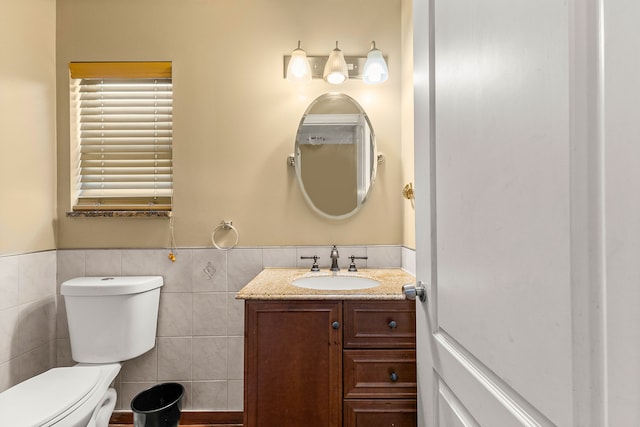 bathroom with vanity, toilet, and tile walls