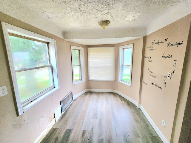 spare room featuring light hardwood / wood-style flooring and a textured ceiling