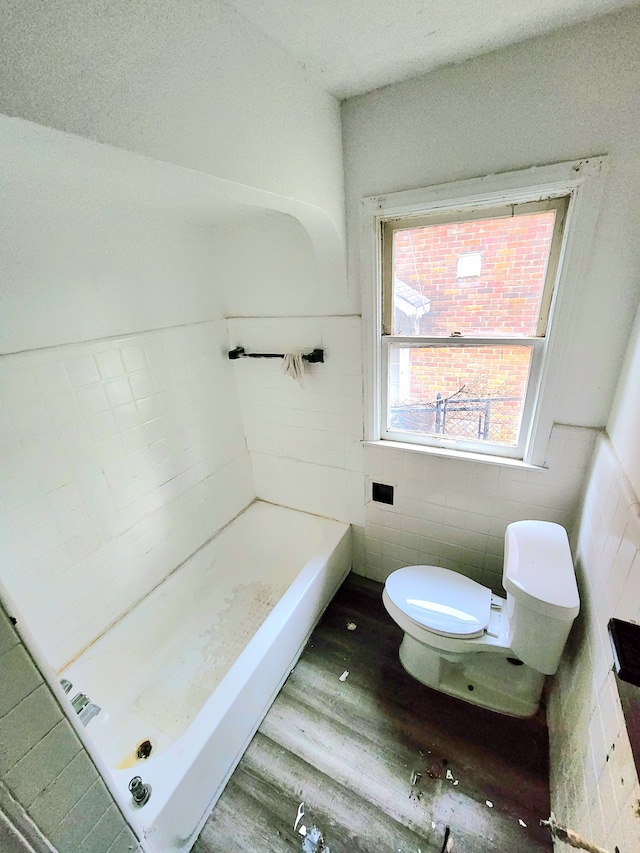 bathroom with wood-type flooring, a bathtub, toilet, and tile walls