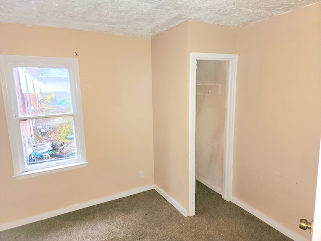 carpeted empty room with a textured ceiling