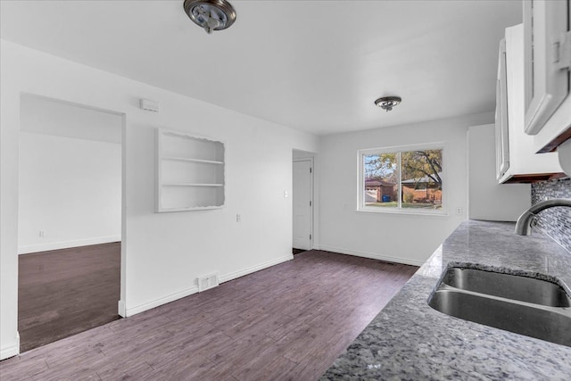 kitchen with dark hardwood / wood-style flooring, stone countertops, white cabinetry, and sink