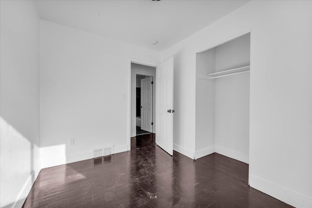 unfurnished bedroom featuring dark hardwood / wood-style flooring and a closet