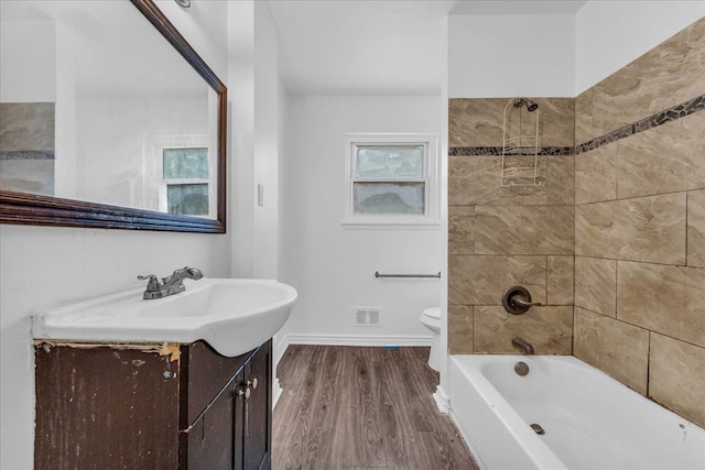 full bathroom with vanity, hardwood / wood-style flooring, toilet, and tiled shower / bath