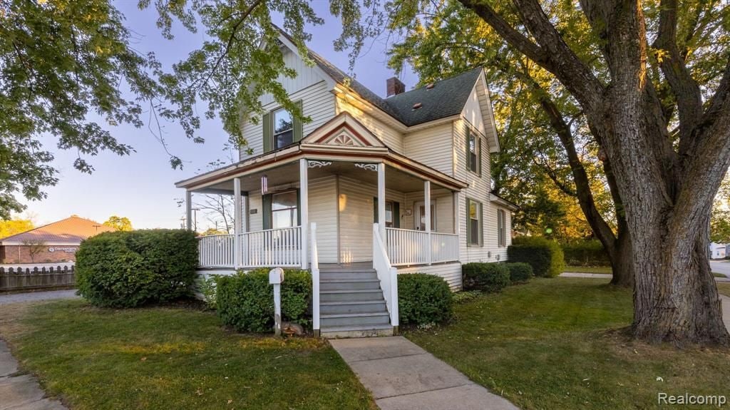 victorian home featuring covered porch and a lawn