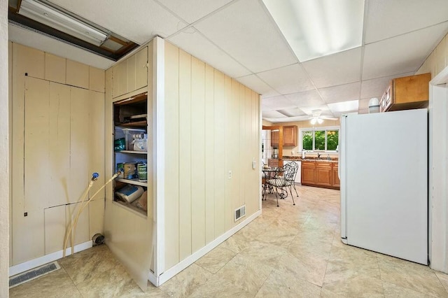 interior space with a drop ceiling and wooden walls