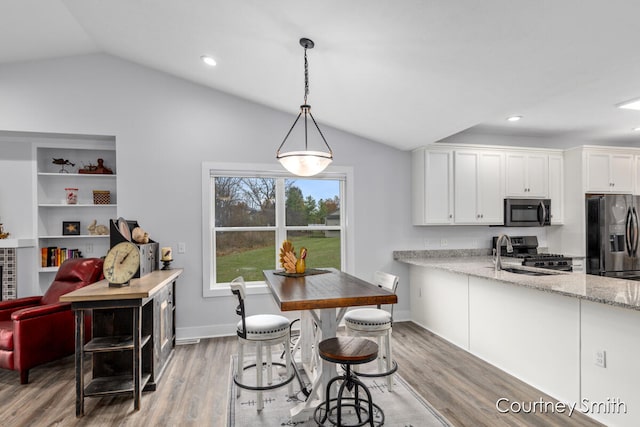 kitchen with sink, light hardwood / wood-style flooring, pendant lighting, lofted ceiling, and appliances with stainless steel finishes