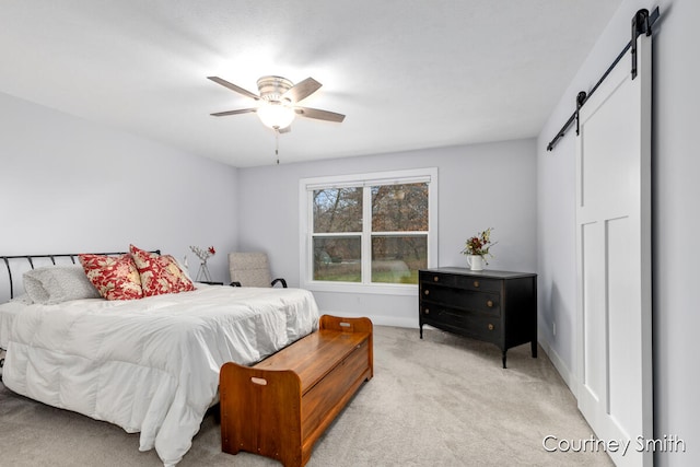 carpeted bedroom with a barn door and ceiling fan