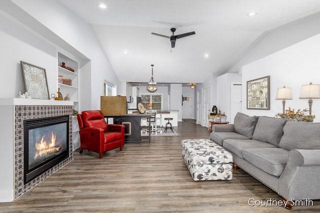 living room featuring ceiling fan, wood-type flooring, a fireplace, and vaulted ceiling