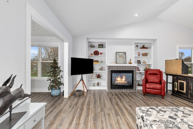 living room with a tile fireplace, wood-type flooring, lofted ceiling, and a wealth of natural light