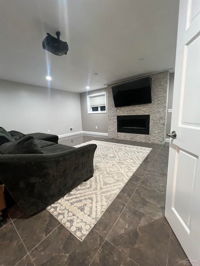 living room featuring dark tile patterned flooring and a stone fireplace