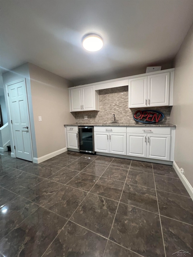 kitchen with tasteful backsplash, sink, white cabinets, and beverage cooler